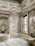 Elaborate interior space featuring intricately carved stone walls with floral and geometric patterns. The design includes arches, columns, and a large window that lets in natural light. The overall architecture displays a luxurious and ornate style.