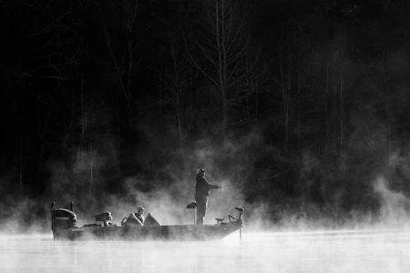 Angler on a calm lake at dawn