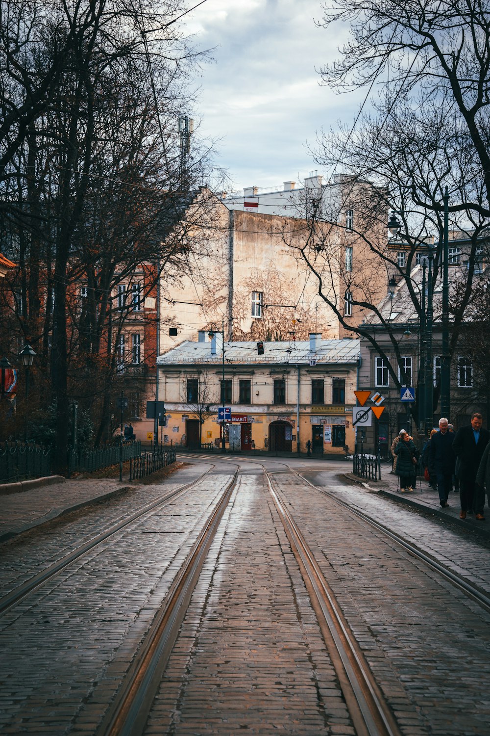 a couple of people walking down a street next to a train track