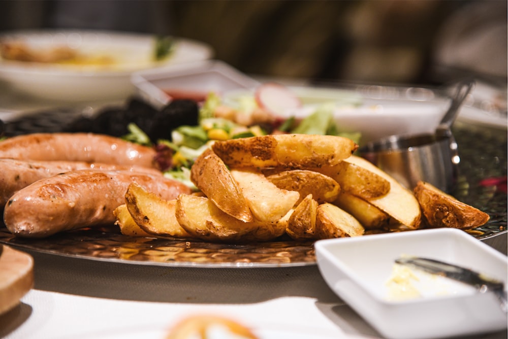 a plate of food with sausages, potatoes and salad