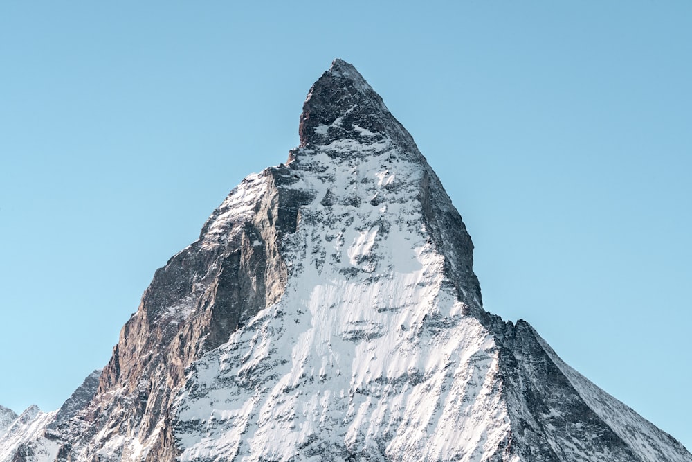 a very tall snow covered mountain with a sky background