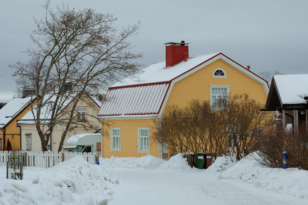 a yellow house with a red roof in the snow
