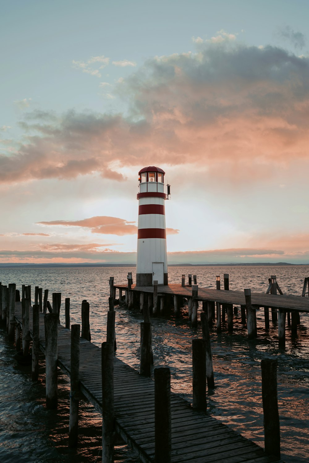 a red and white light house sitting on top of a pier