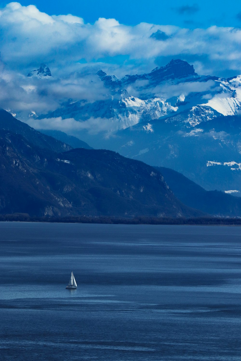 a sailboat in a large body of water with mountains in the background