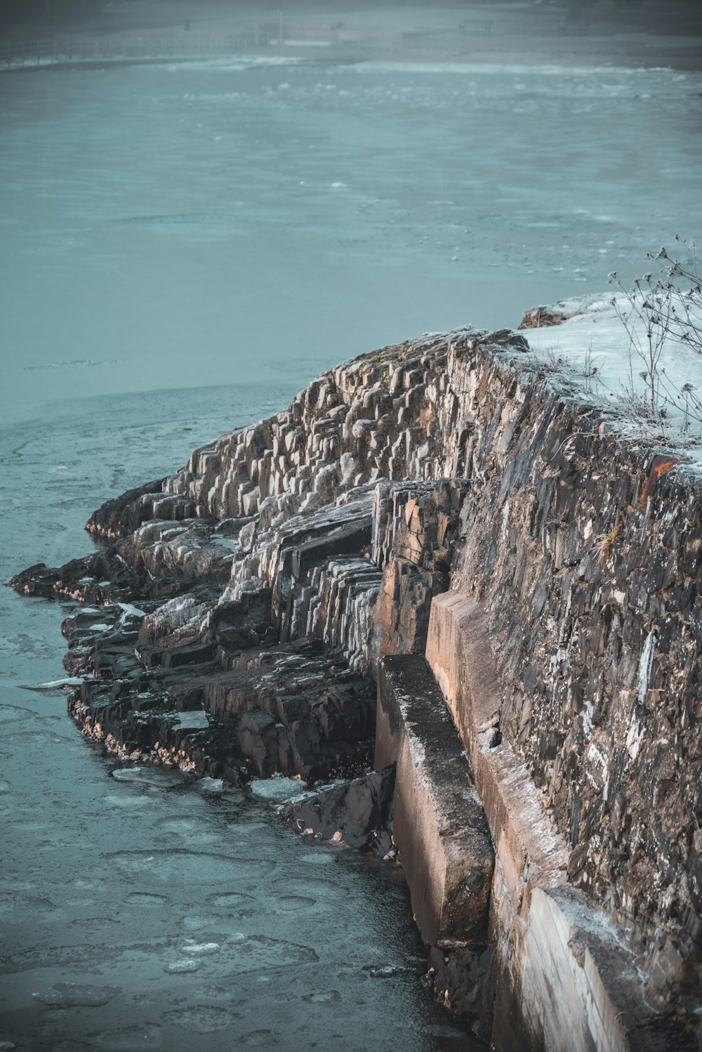 a stone wall next to a body of water