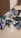 A collection of various sneakers is arranged on a tiled floor. The sneakers come in different styles and colors, featuring brands like Nike and Adidas. The shoes exhibit hues such as blue, black, white, and a pair in gray with a yellow sole.