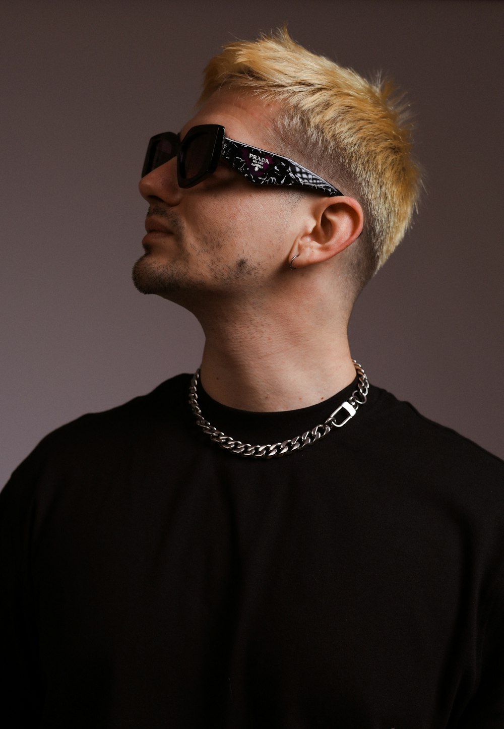 a man with blonde hair wearing sunglasses and a chain around his neck