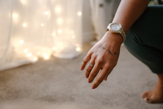A diamond-encrusted watch gleaming on a wrist with tattoos
