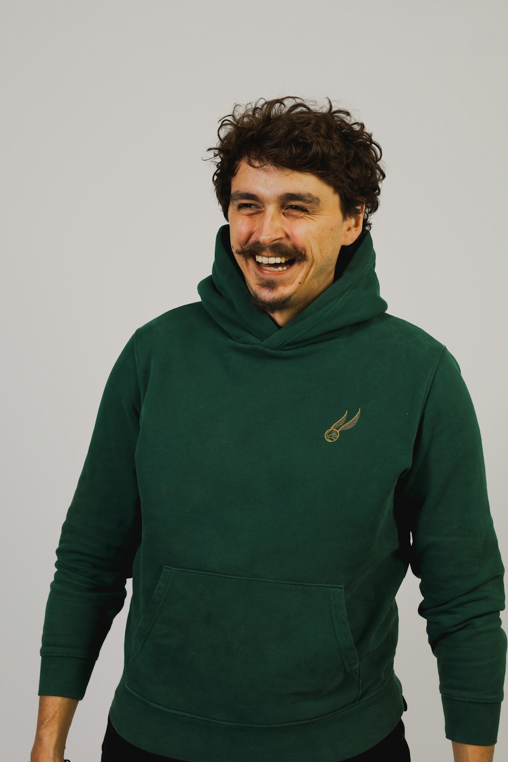 a man wearing a green hoodie with a smile on his face