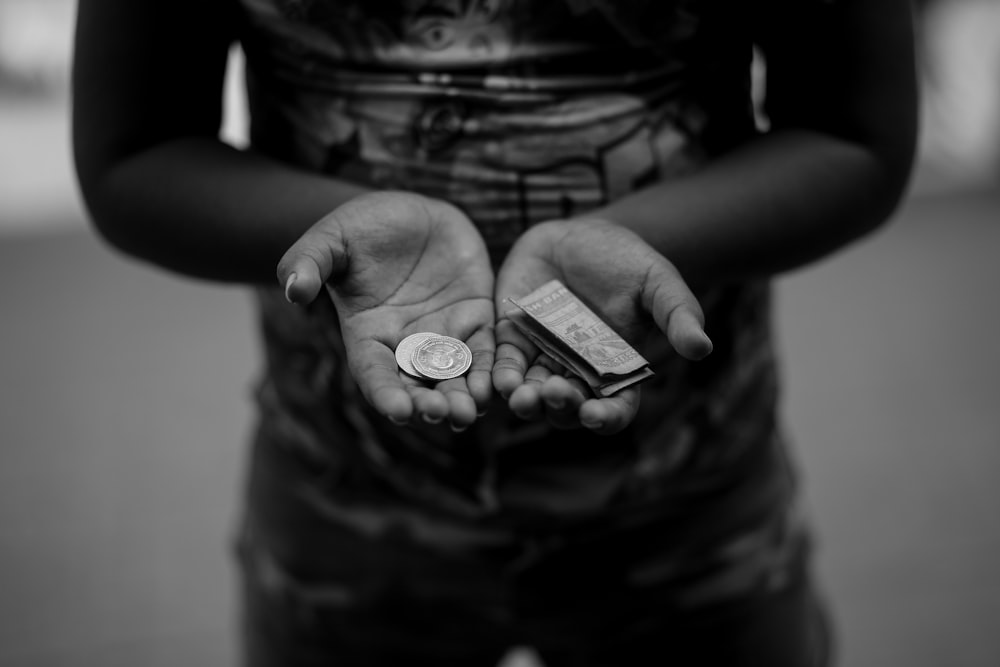 a black and white photo of a person holding a coin