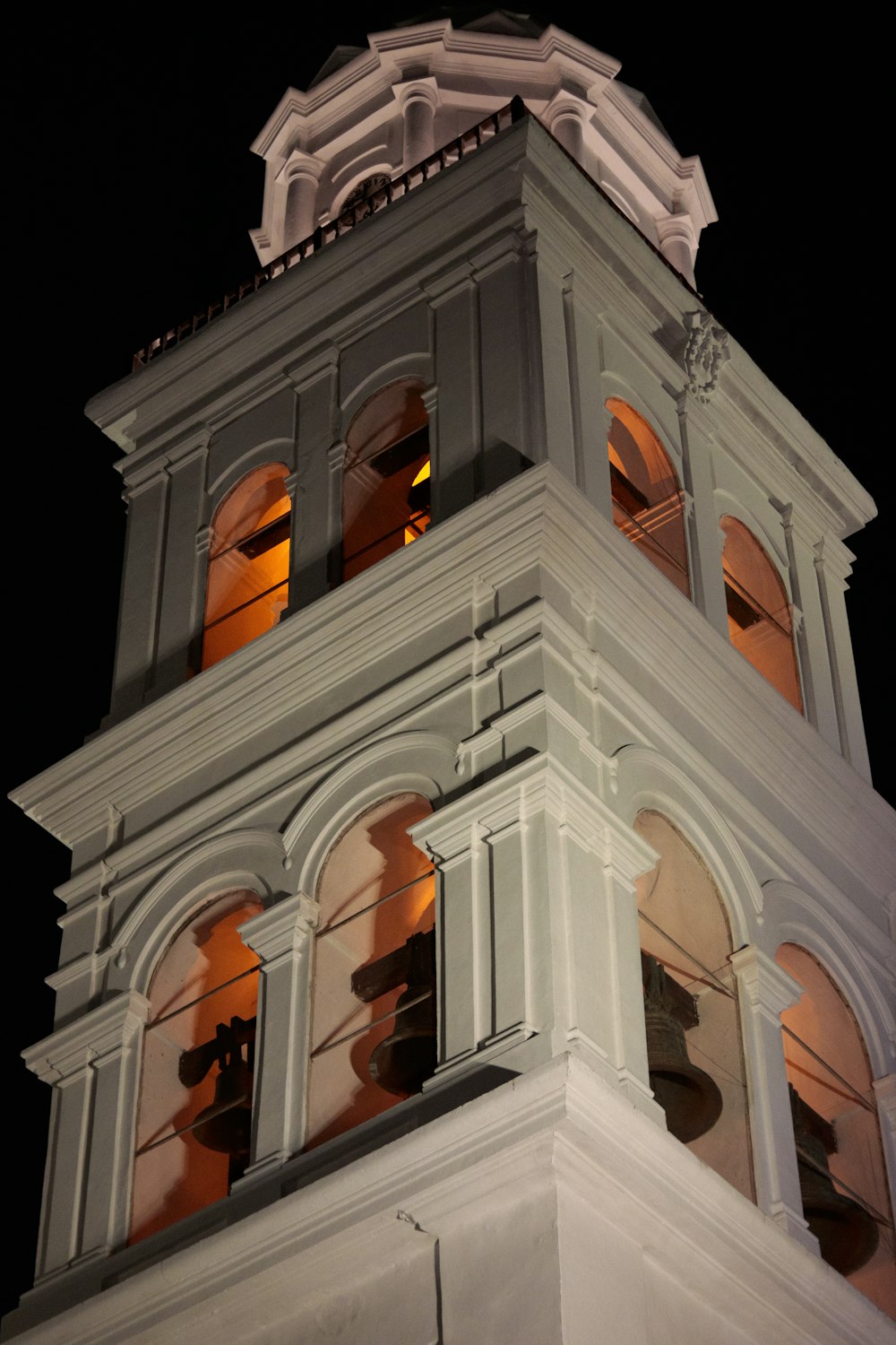 uma torre do relógio branca alta com um relógio em cada um dos lados