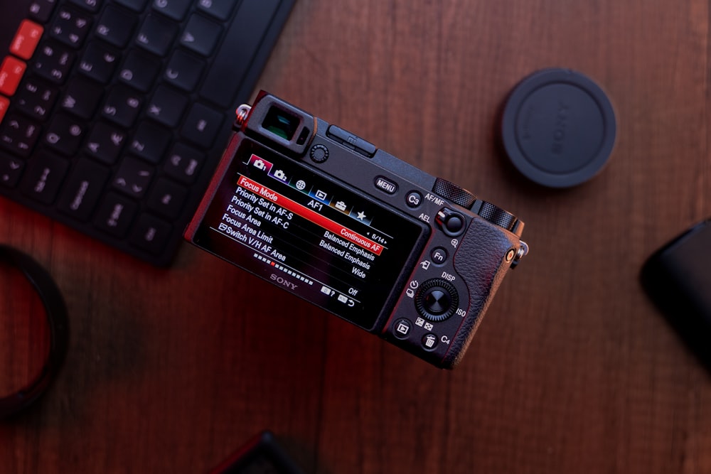 a camera sitting on top of a wooden table next to a keyboard