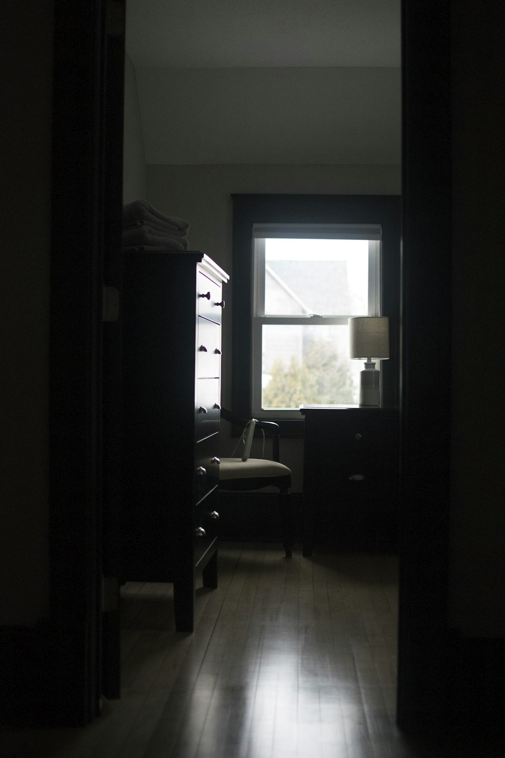 a dark room with a chair and a window