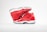 A pair of bright red high-top athletic shoes is positioned in a dynamic pose against a simple white background. The shoes feature a glossy finish with a distinct logo in black on the side. The soles are thick and white with a semi-transparent section.