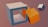 A 3D render features a large, hollow, light gray cuboid with an orange cube partially placed inside it. Another smaller cube, colored in a gradient of purple and white, floats nearby on a plain muted background.