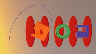 A series of abstract geometric shapes are arranged on a flat surface. There are elongated red ovals placed horizontally, alongside an orange angular shape resembling a house, a green circular gear, and a purple rectangular block. A purple curve arcs over the composition from left to right. The background transitions from dark yellow on the left to beige on the right.