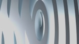 An abstract 3D design featuring curved and overlapping smooth surfaces. The image has a metallic-like texture with varying shades of gray and hints of light blue.