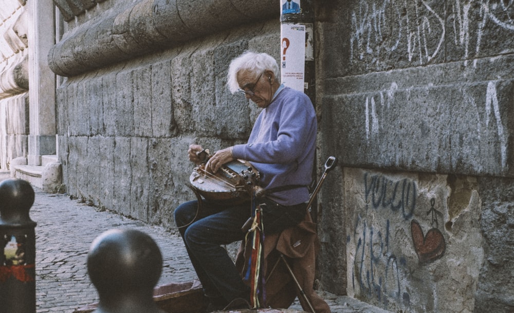 a man sitting on the side of a building next to a wall