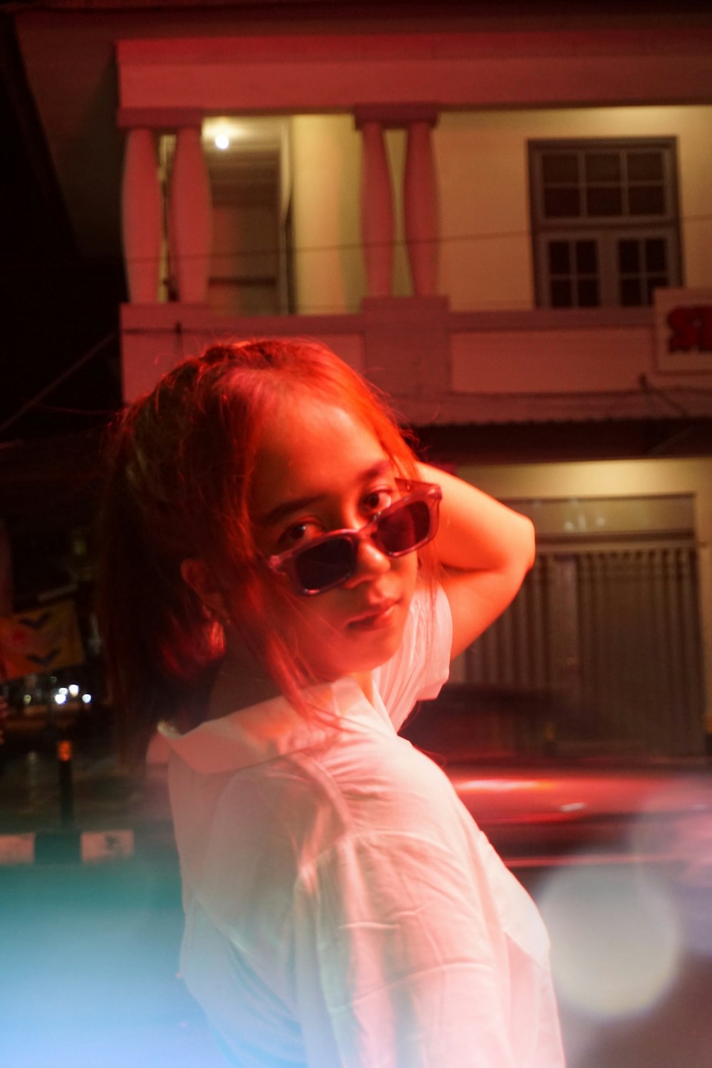 a girl in sunglasses standing in front of a building
