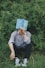 a man sitting in the grass with a book on his head