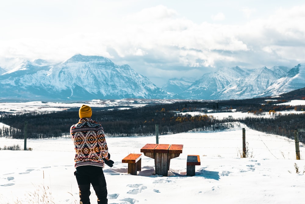 a person standing in the snow with mountains in the background