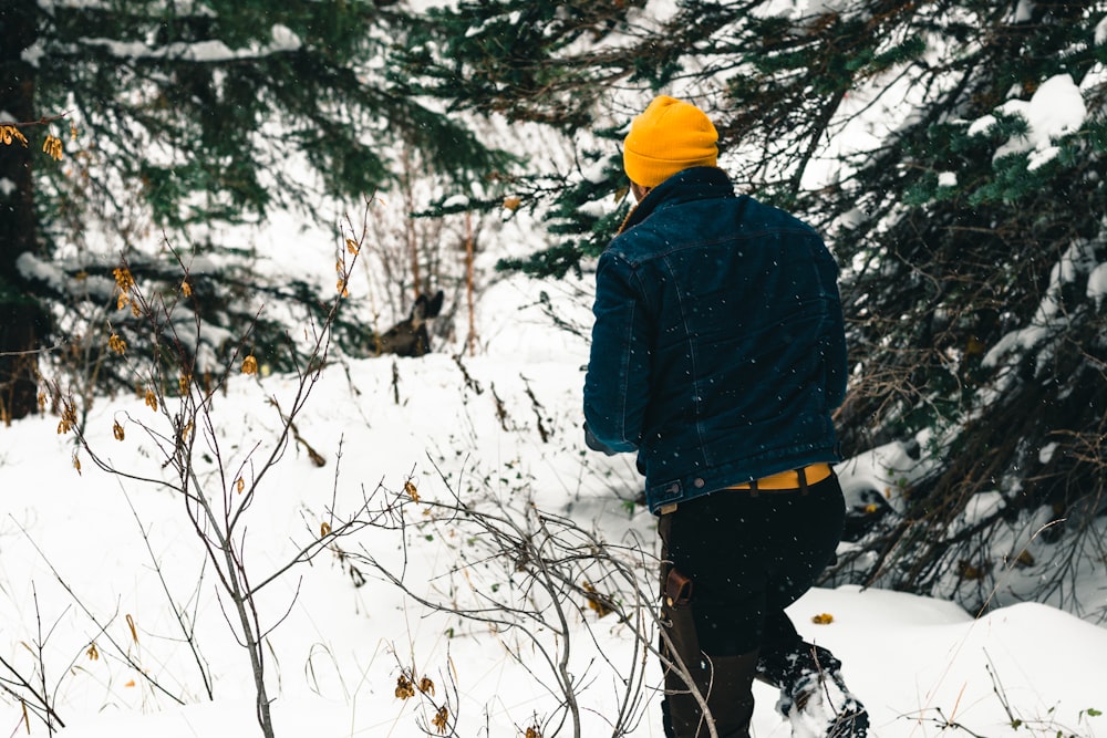 a man in a yellow hat is walking through the snow