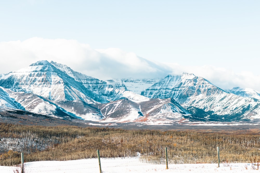 a snow covered mountain range with a fence in the foreground