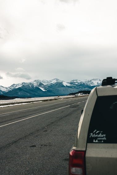 A cozy Dzire taxi parked by a scenic mountain road near Chamoli, ready for a comfortable journey.