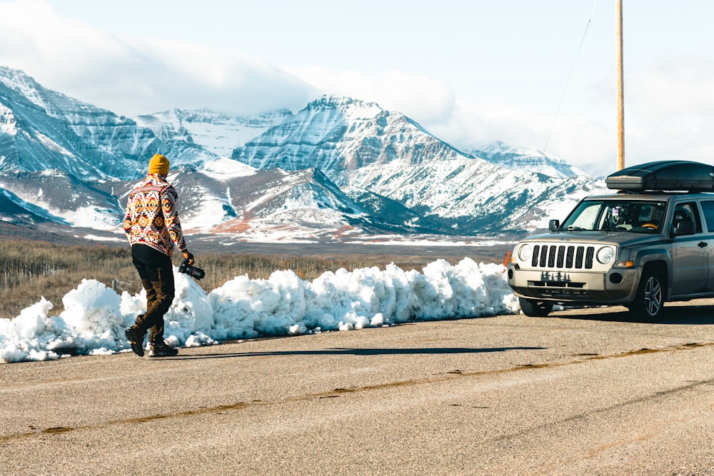 a man walking down a road next to a jeep