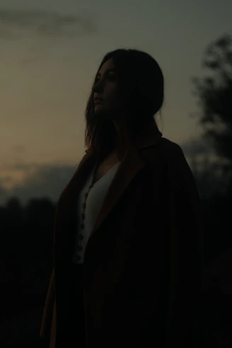 a woman standing in front of a sunset