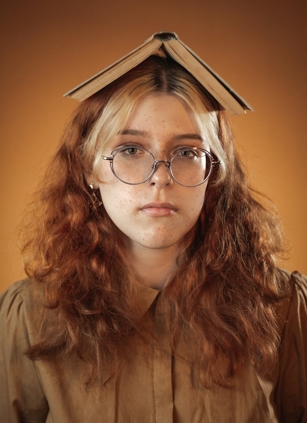 a woman with glasses and a book on her head