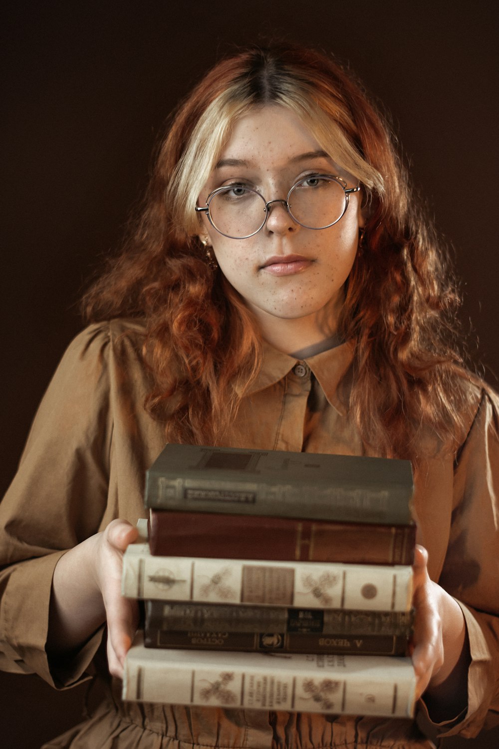 a woman holding a stack of books in her hands