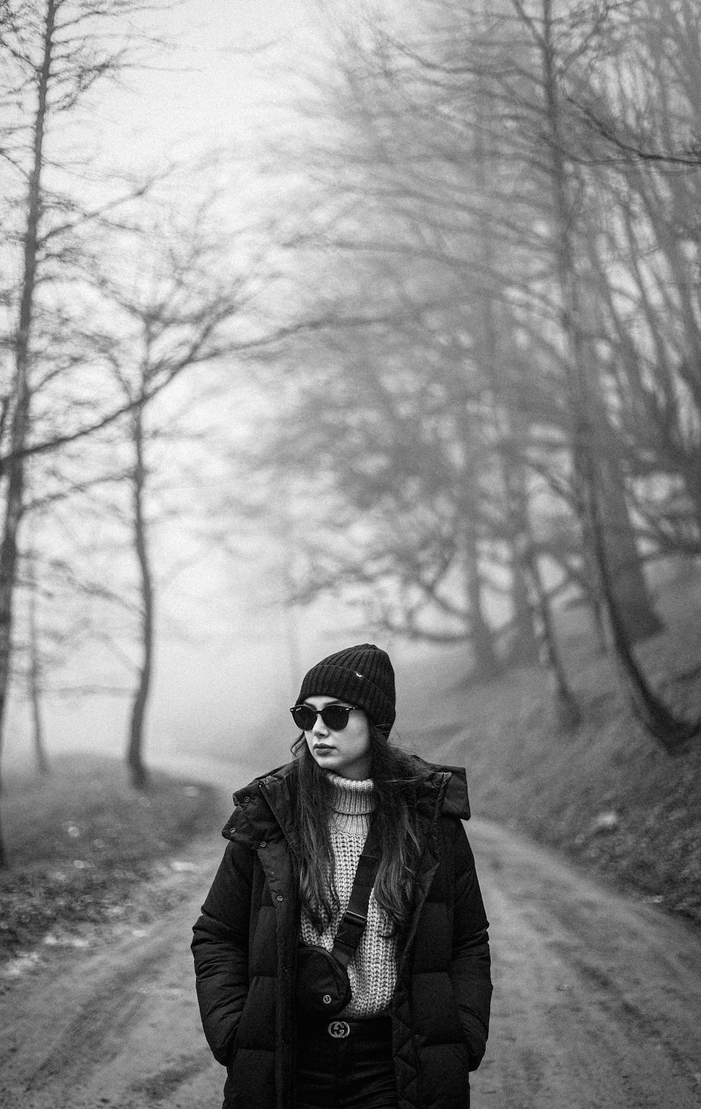 a woman standing on a dirt road in the woods