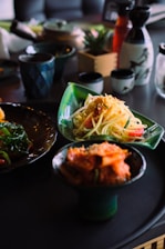 A colorful spread of homemade dishes combining Italian pasta and Korean side dishes on a rustic wooden table ready for a family gathering.