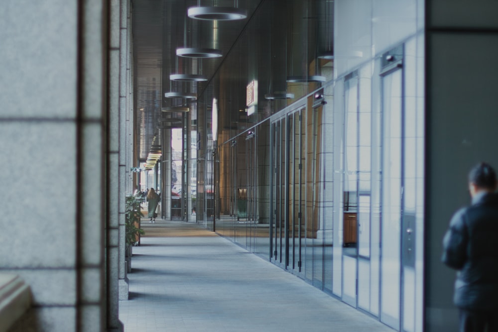 a man walking down a hallway next to a tall building