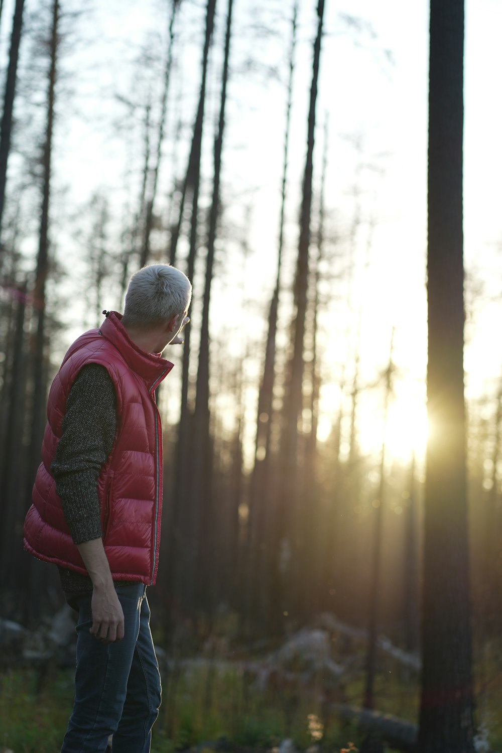 a man in a red vest standing in a forest