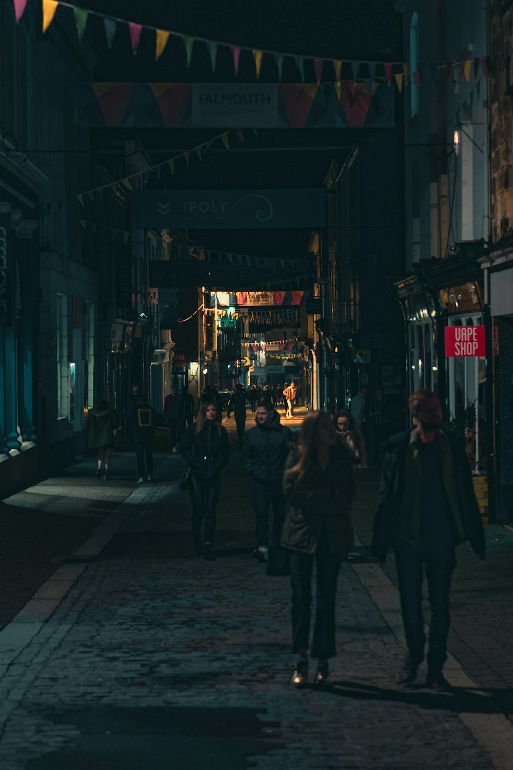 a group of people walking down a street at night