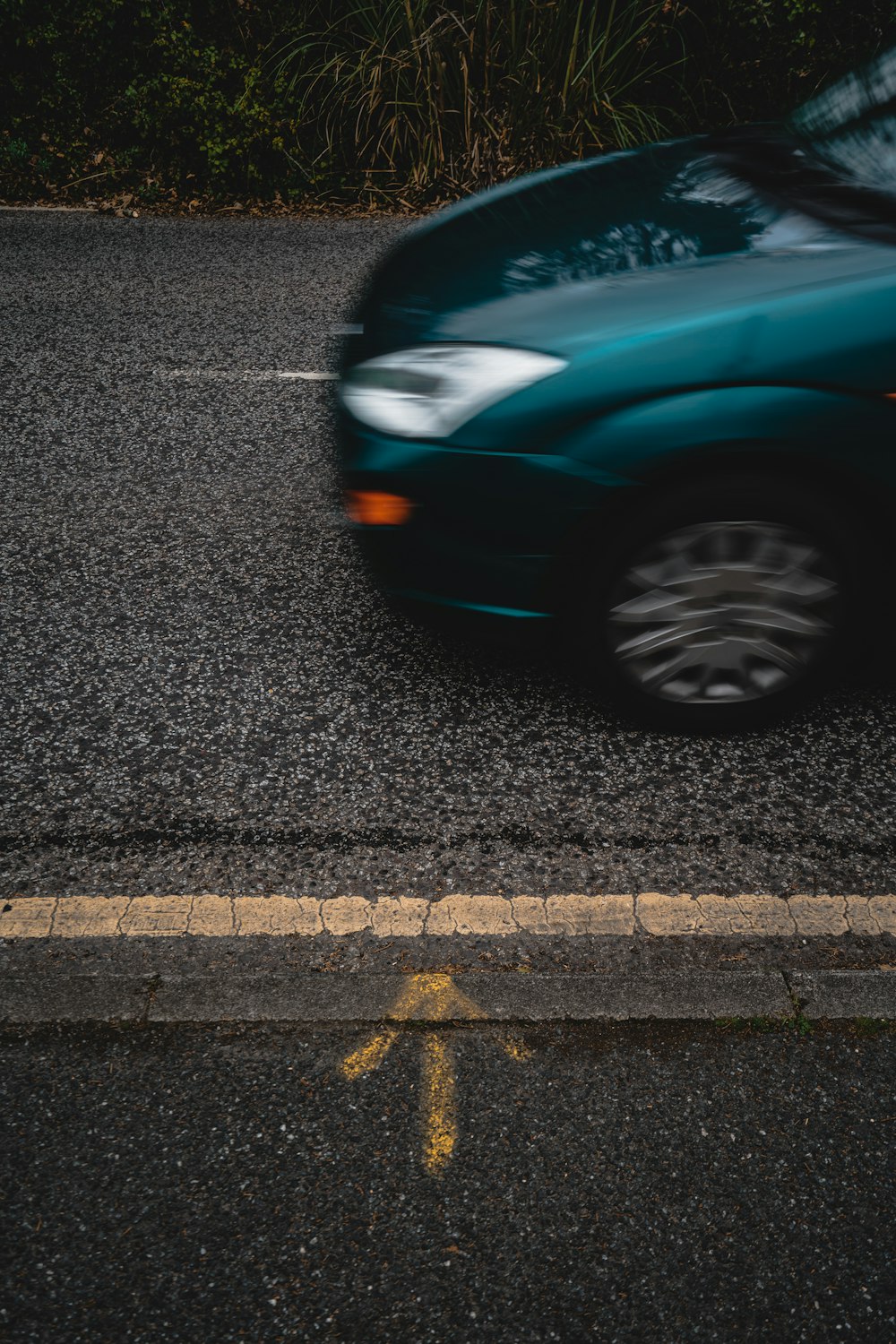 a blue car driving down a street next to a curb