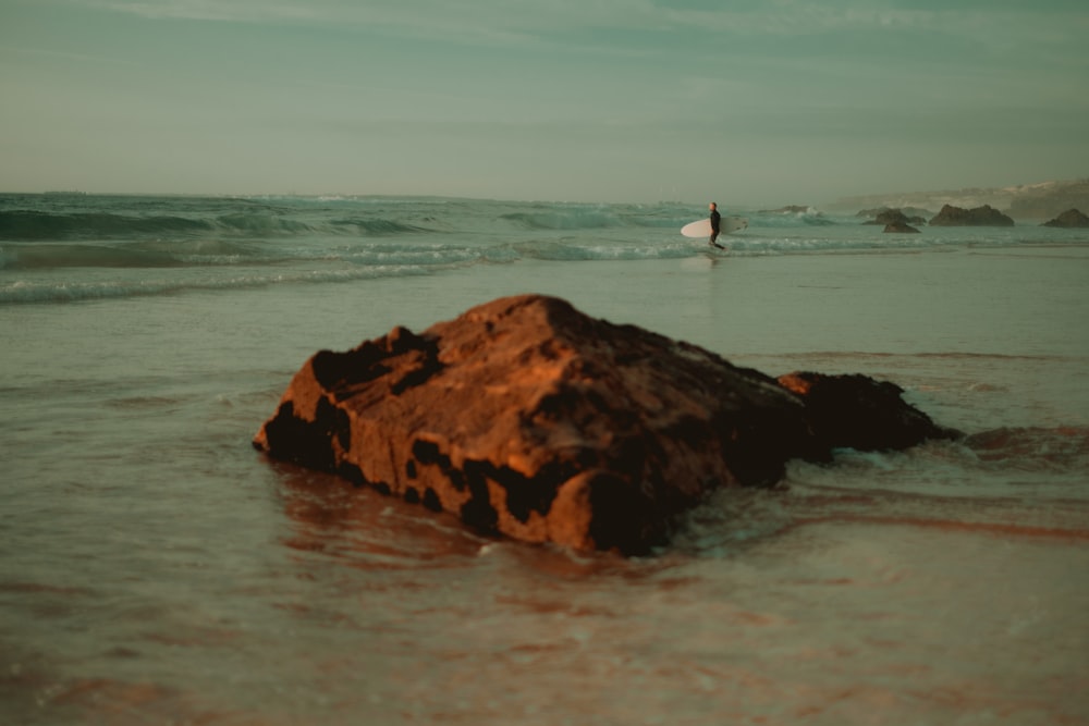 a person standing in the ocean with a surfboard