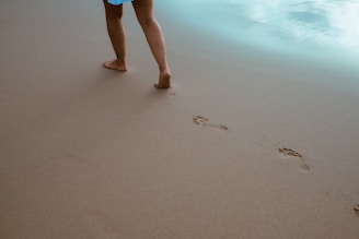 a person walking on a beach with footprints in the sand