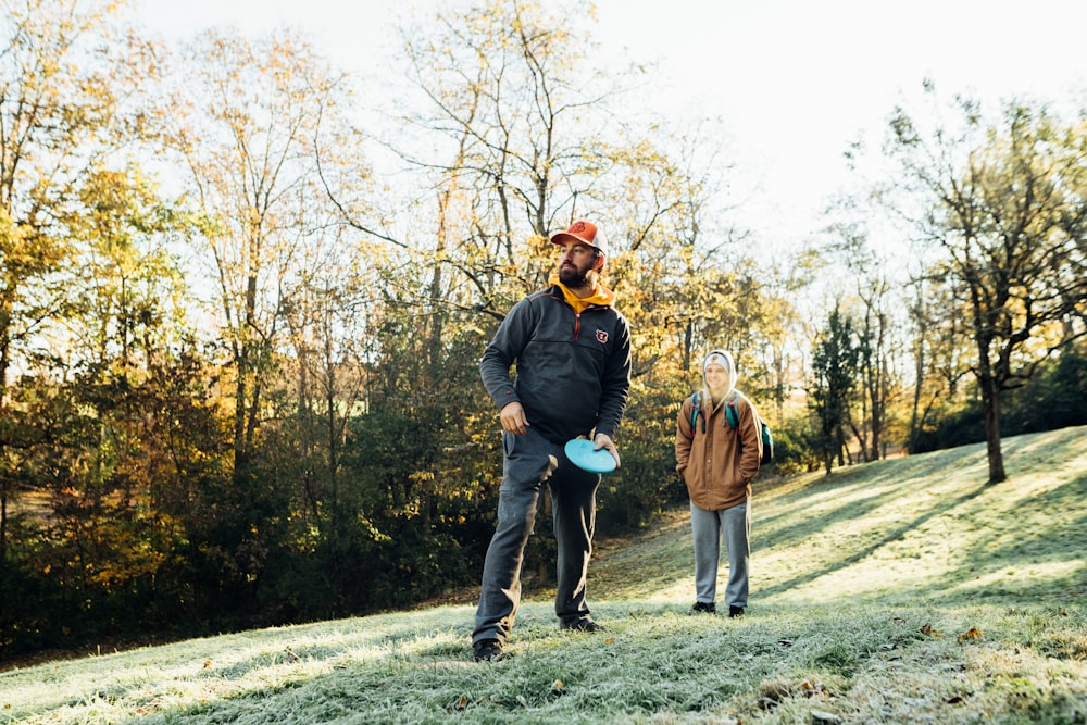 a man holding a frisbee while standing next to another man