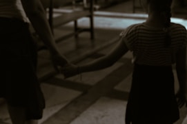 a young girl holding the hand of an older woman