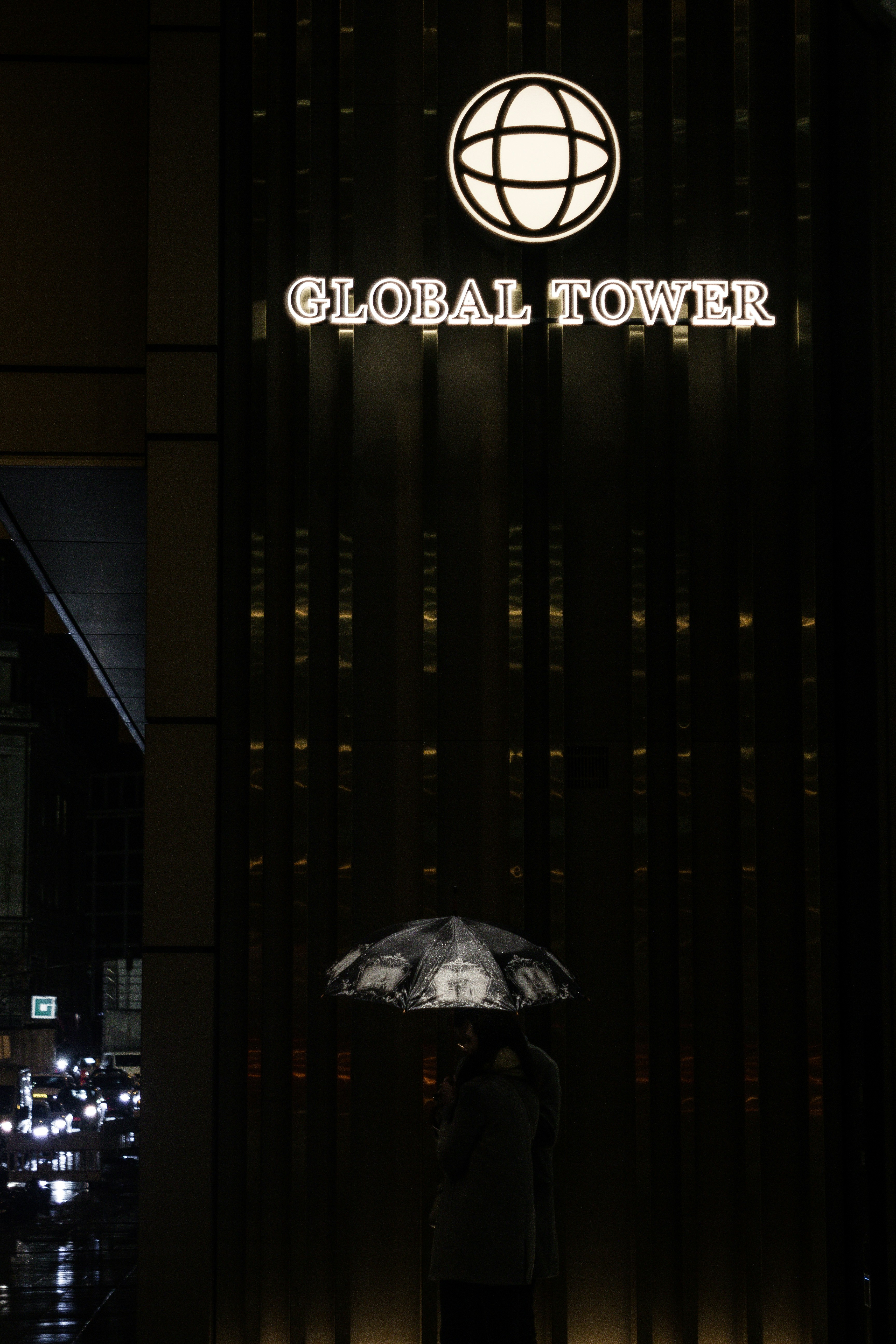 two people standing under an umbrella in front of a building