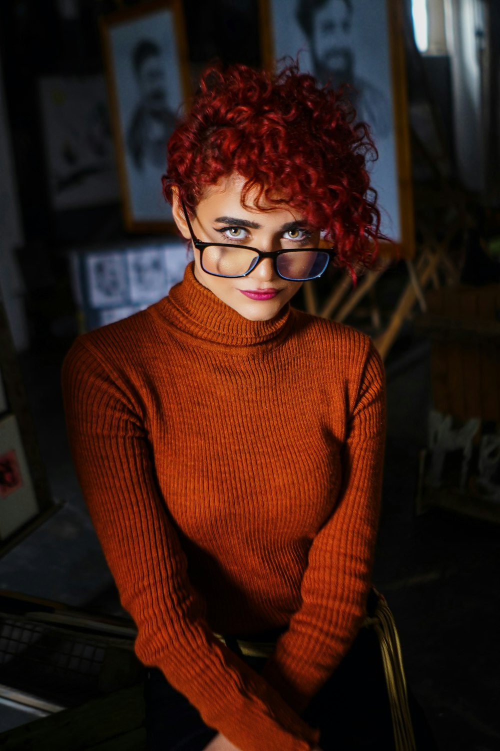 a woman with red hair and glasses sitting in a chair