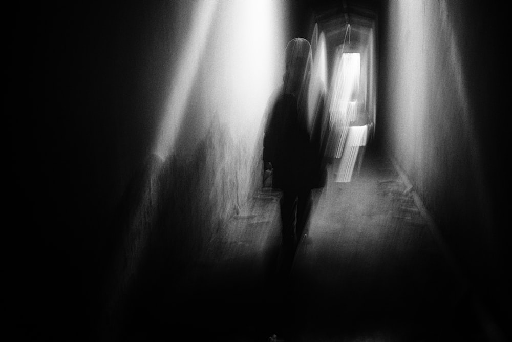 a black and white photo of a person walking down a hallway