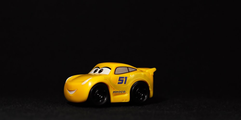 Ein gelbes Spielzeugauto, das auf einer schwarzen Fläche sitzt
