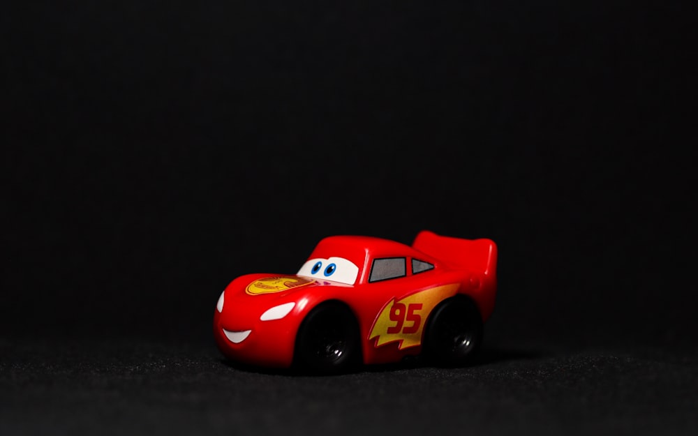 une petite voiture rouge posée sur une surface noire
