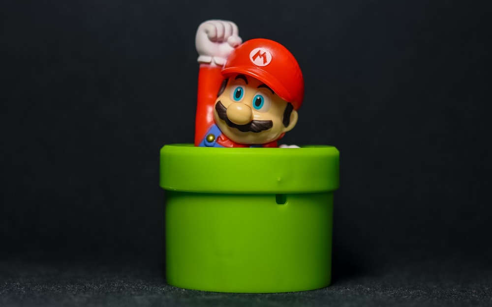 Eine Nintendo Mario Figur sitzt in einer grünen Tasse