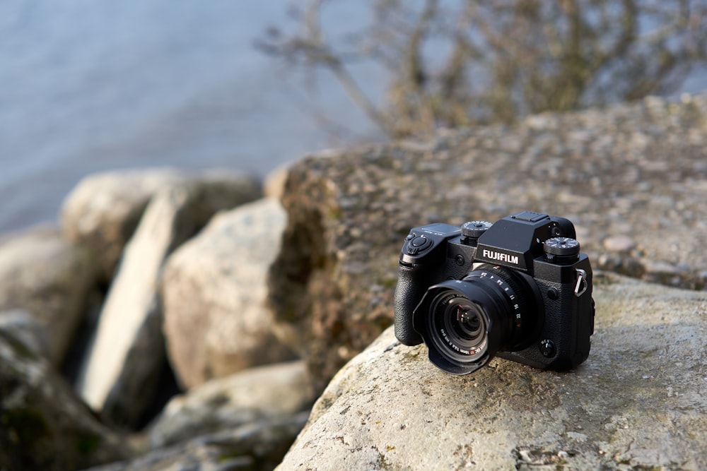 a camera sitting on top of a rock next to a body of water