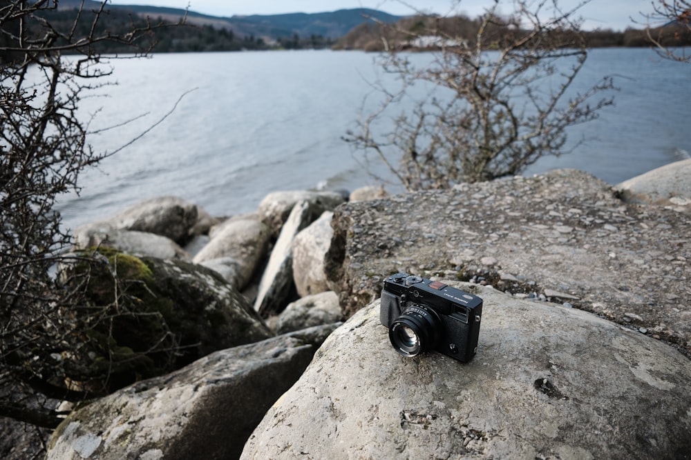 a camera sitting on top of a rock next to a body of water